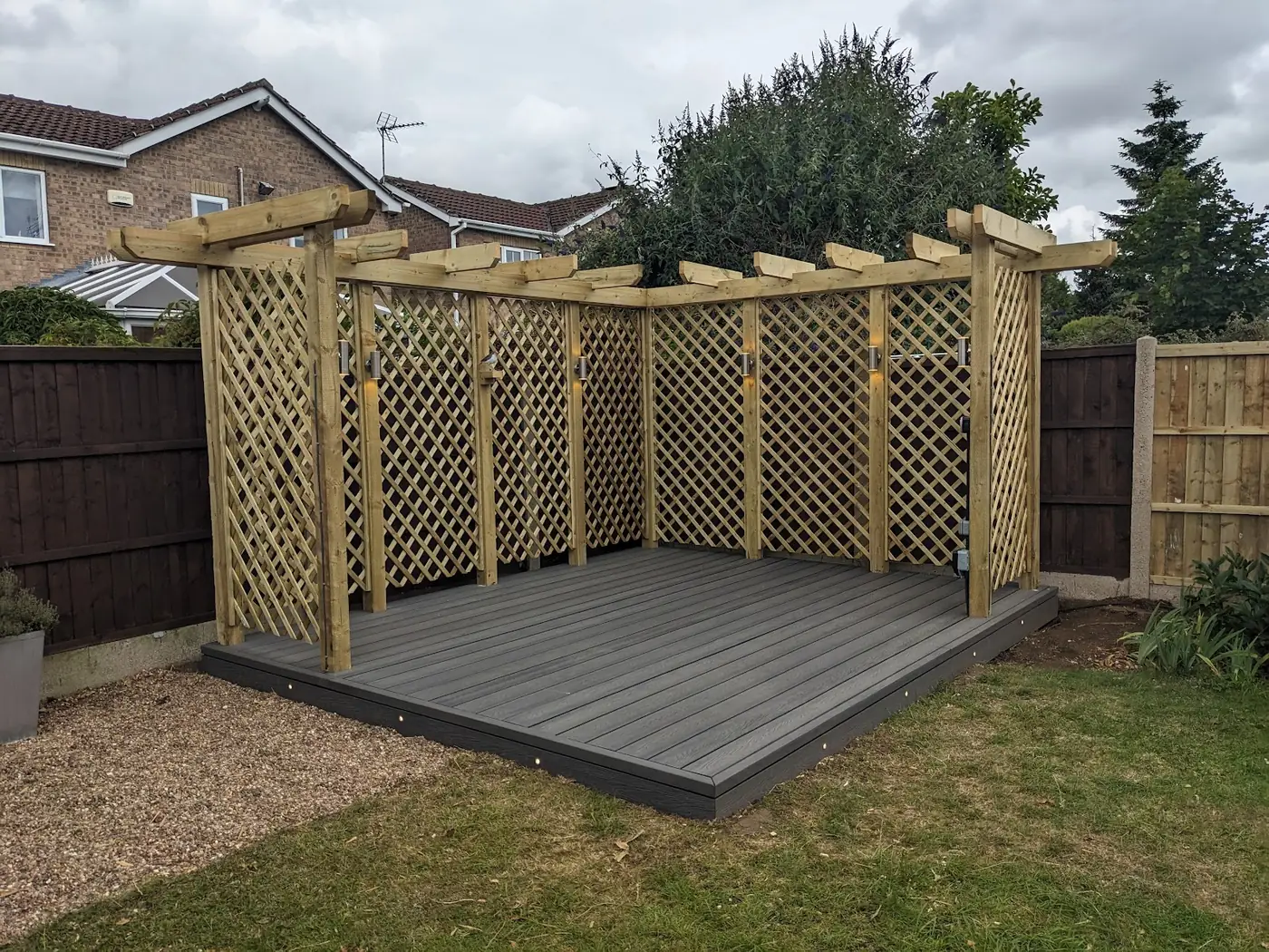 Grey composite deck under a timber pergola with lattice screens