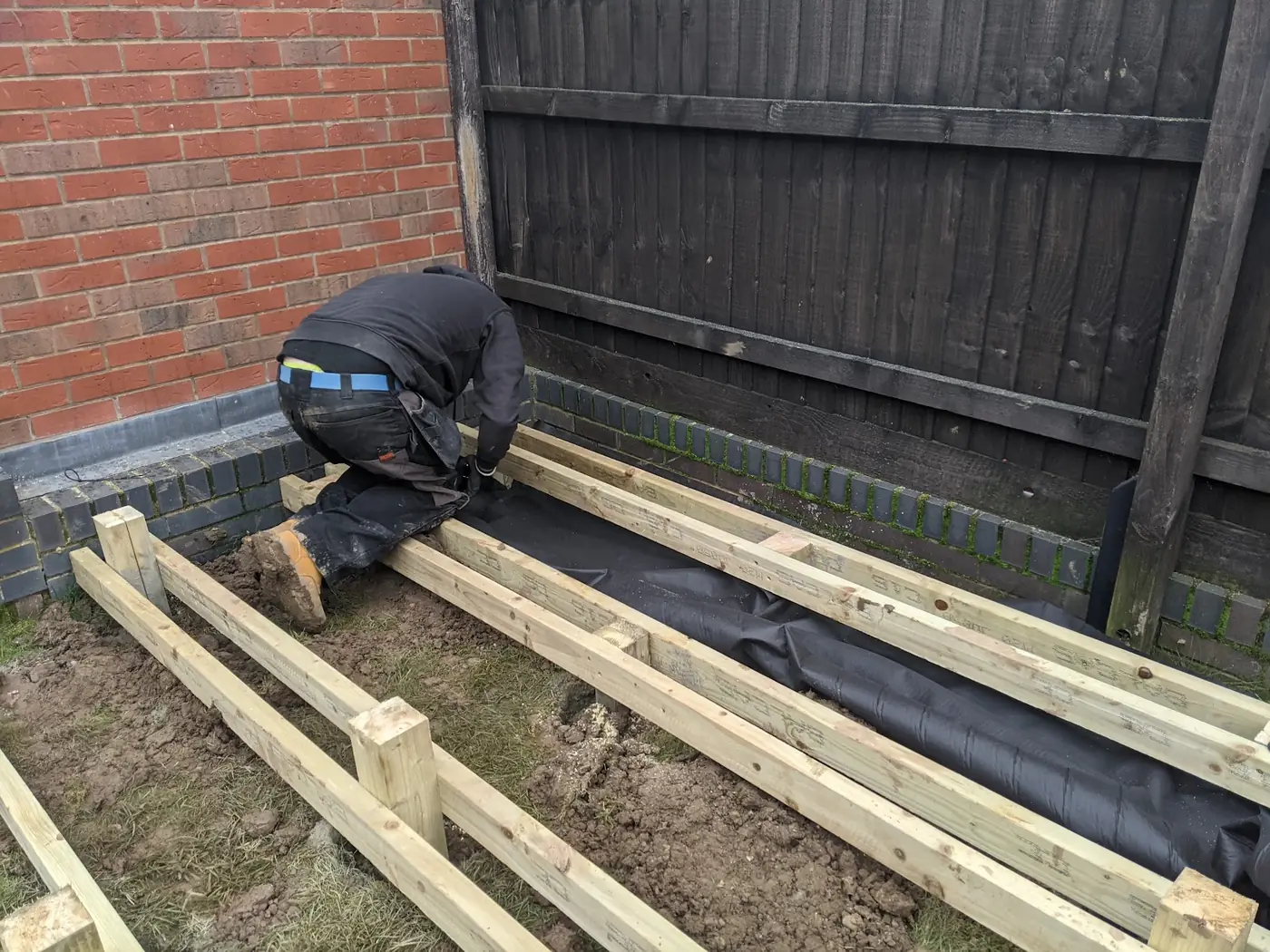 A new deck frame of treated joists being laid on weed membrane